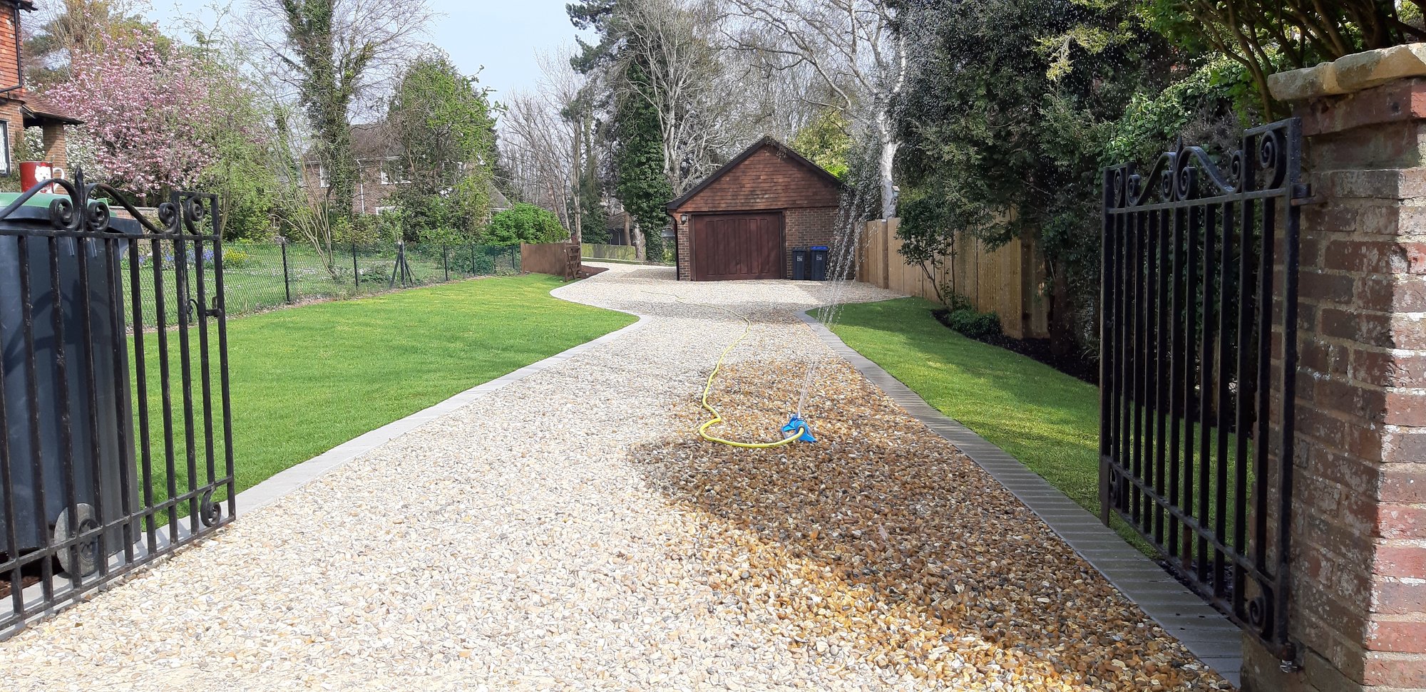 Gravel driveway with wrought iron gates and landscaped lawn